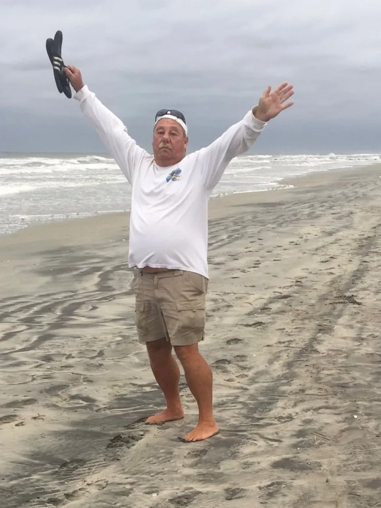Scott holding his hands up at the beach